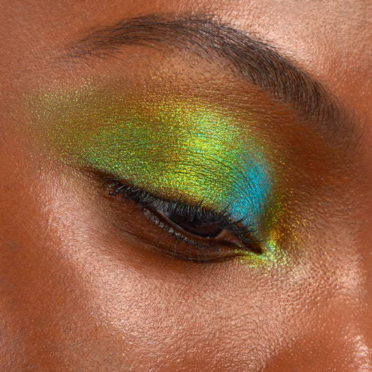 Beetle ColourPop Chrome Liquid Shadow shifts lime green, gold, and teal on a closed eyelid in a macro swatch, reflecting a bold multichrome sheen with high-shine metallic payoff and smooth, opaque coverage.