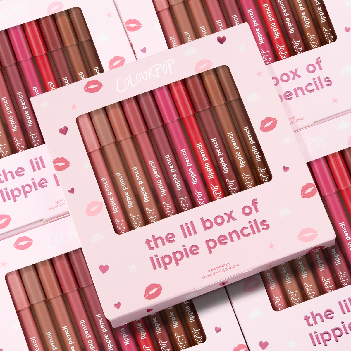 ColourPop Lippie Pencil set presenting The Lil Box of Lippie Pencils, a multi-shade lip liner kit displayed in a pink box with a clear window; pencils in nude, pink, and red tones lined up, with stacked kiss-print packaging in the background.