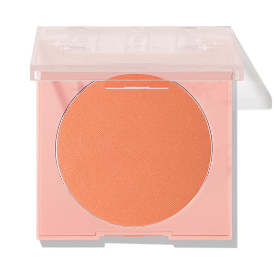 ColourPop Pressed Powder Blush in Pretty Toasty, a warm peachy apricot shade, rests in a pale pink square compact with a clear lid partially open against a clean studio background.