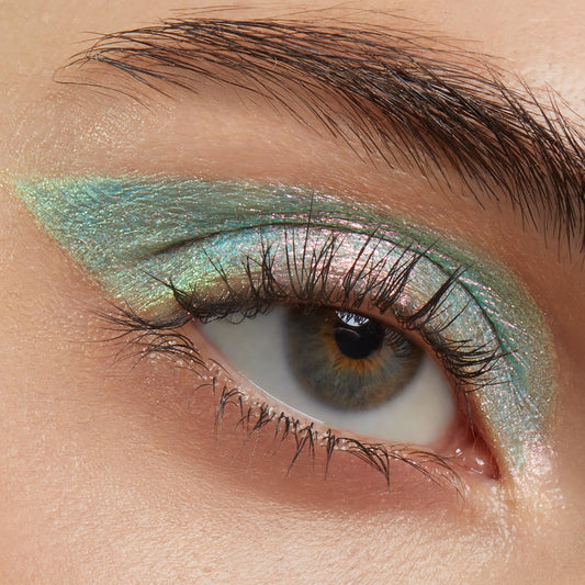 Close-up eye wearing Colourpop Game Over Shadow Stix, showing iridescent teal and pink shimmer eyeshadow blended in a sharp wing across the lid for bold metallic payoff.