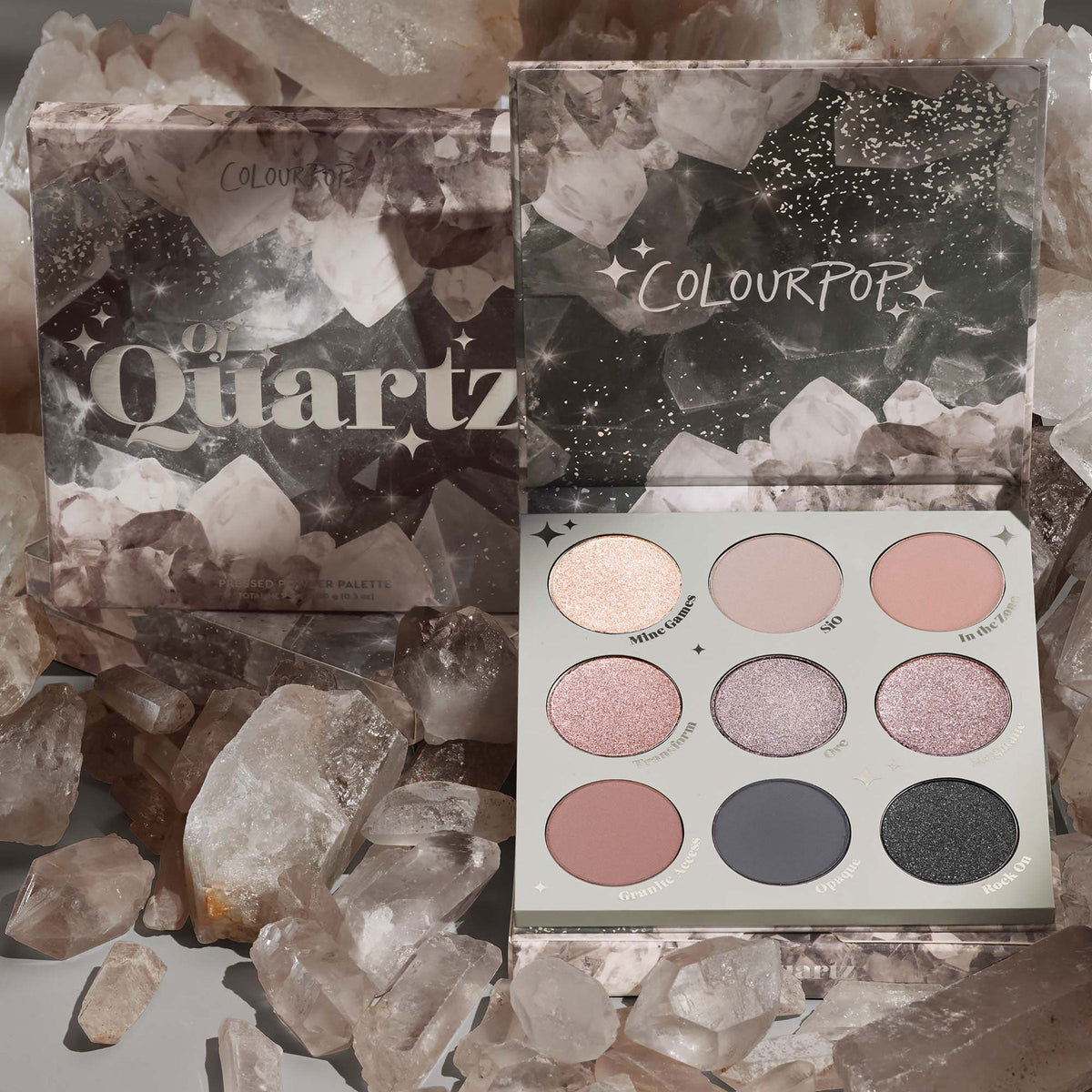 ColourPop Of Quartz shadow palette showcases nine cool-toned pressed powder shades - a mix of shimmers and mattes - in an open 3x3 compact beside its crystal-print box, arranged among smoky quartz rocks.