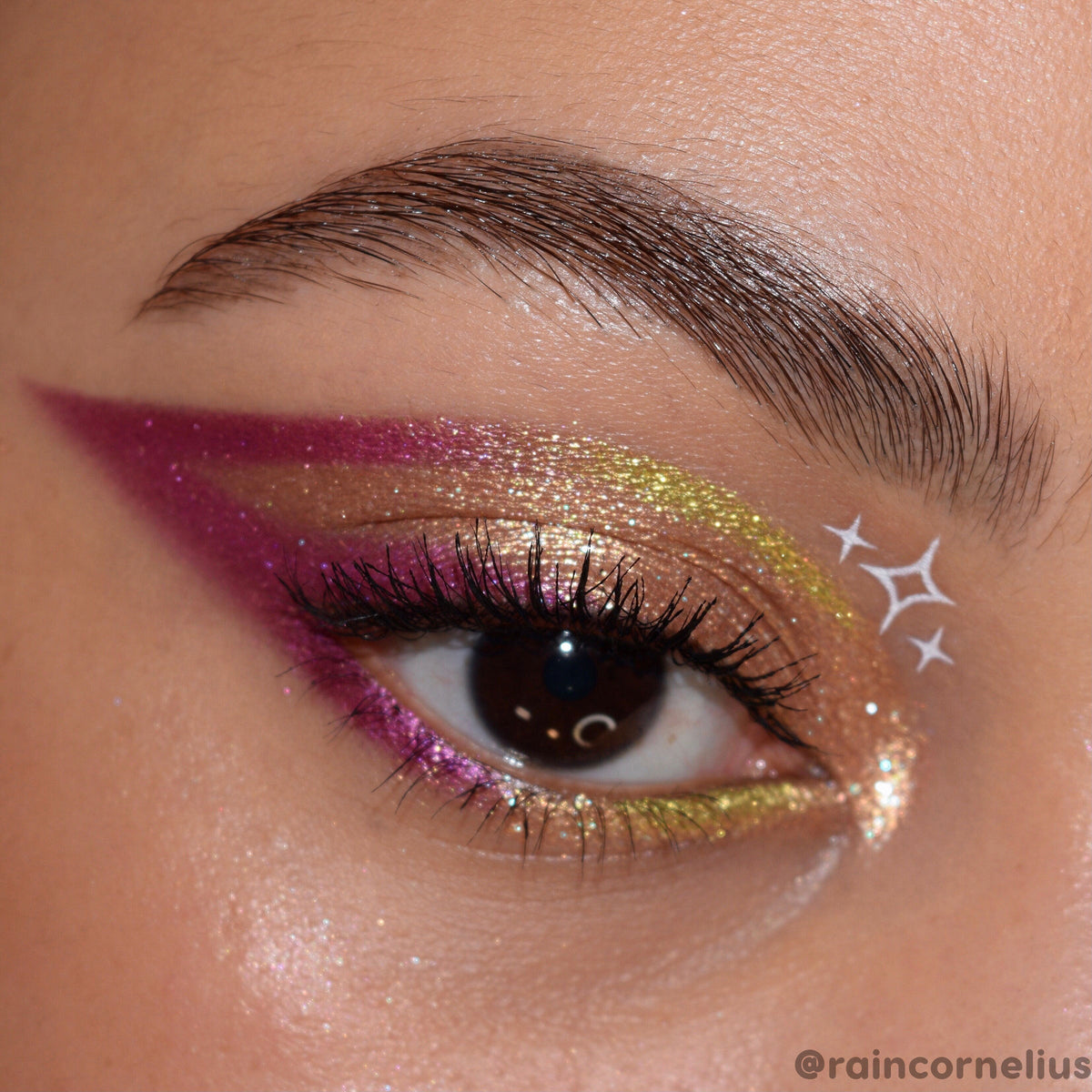 Green Juice ColourPop Super Shock Shadow sweeps a lime‑gold shimmer across the eyelid, paired with a bold magenta wing, glittered lower lash line, and white star decals in a close‑up eye look showcasing metallic payoff and sparkle.