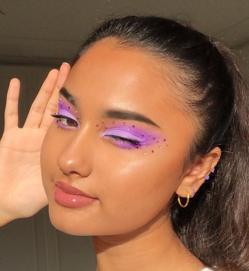 Violet gradient eye makeup created with the Fade Into Hue ColourPop Shadow Palette, model winks as rhinestones trace the lids in natural sunlight, showcasing the blendable pigment and rainbow tones of this shadow palette.
