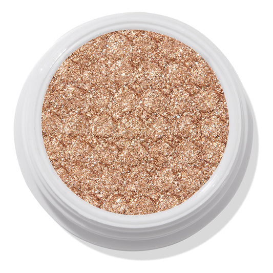 A Little Quarky Super Shock Shadow by ColourPop - sparkly warm champagne–rose gold pigment - fills a round white pot, shimmering with ultra-glitter texture in a close-up studio shot on a white background.