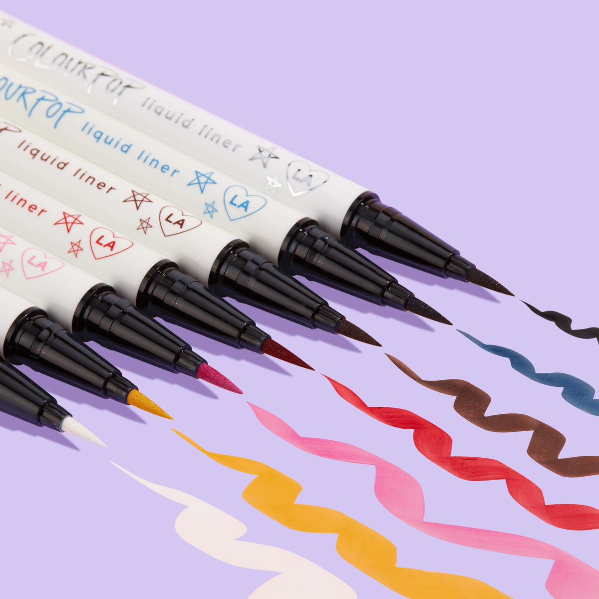 ColourPop Graceland BFF Liquid Liner creates a bold white squiggle beside multicolor swatches, the felt‑tip pen and doodled white barrel angled on a lavender background, showcasing precise application and opaque, quick‑dry wear.