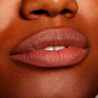 Full lips wearing All My BFFs, a warm rosy-brown nude ColourPop Lippie Pencil, lining and filling the mouth with a creamy satin finish on deep skin in a tight close-up, highlighting precise definition and smooth texture.