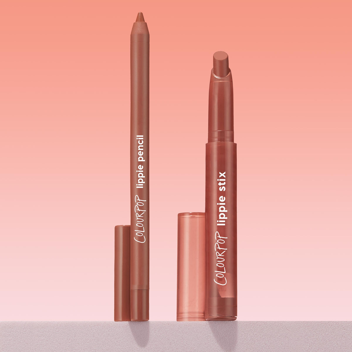 Brat Pack Lippie Stix and ColourPop Lippie Pencil duo standing upright with caps off, revealing creamy mauve‑nude tips on a minimalist ledge against a pink gradient background, highlighting a coordinated lip liner and lipstick set.