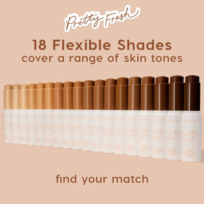 ColourPop Pretty Fresh Tinted Foundation Balm sticks lined up in a gradient of 18 flexible shades - from fair to deep - on a blush-beige backdrop, showcasing inclusive coverage; white tubes with peach script, including shades like Medium 12.