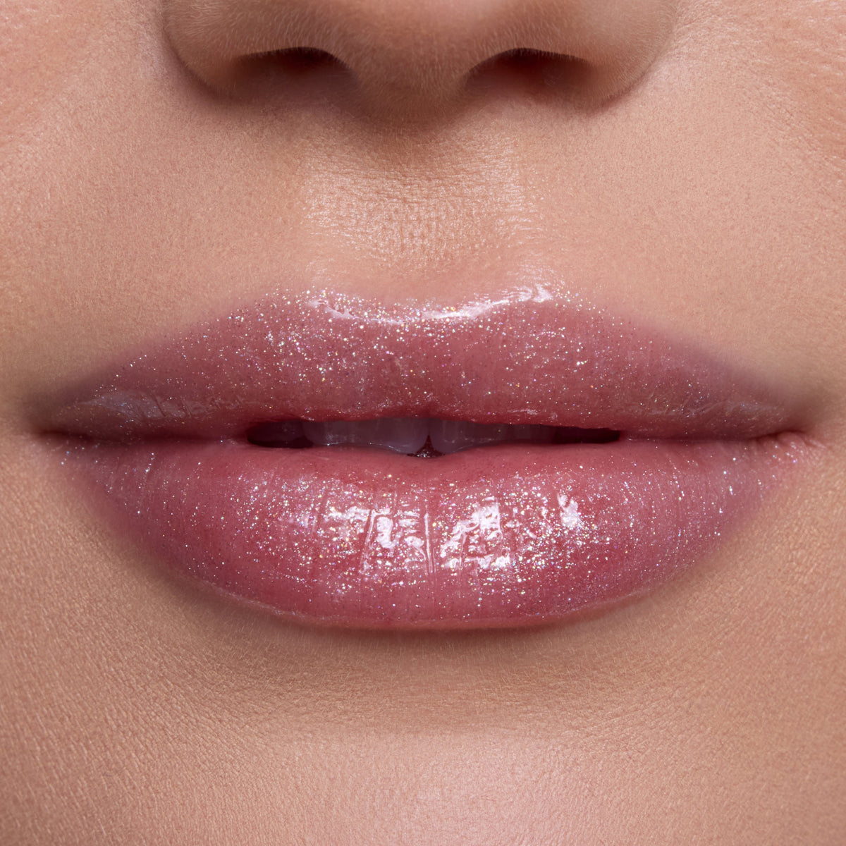 Close-up of lips wearing Bright Ariel Ultra Glossy Lip, a shimmering pink Disney Princess lip gloss with high-shine, reflective sparkle on smooth, fair skin, showcasing moisturizing, ultra-glossy finish for everyday glam makeup looks.