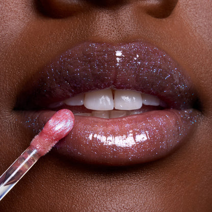 Close-up glossy lips wearing Courageous Rapunzel Ultra Glossy Lip, a shimmery purple-pink Disney Princess lip gloss, as a wand applicator glides on sparkling color for a high-shine finish.