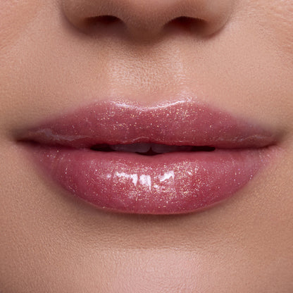 Close-up lips wearing Mademoiselle Belle Ultra Glossy Lip, a shimmery pink Disney Princess lip gloss with high-shine, sparkly finish on smooth, light-toned skin, showing moisturizing, ultra-gloss texture for a glam beauty look.
