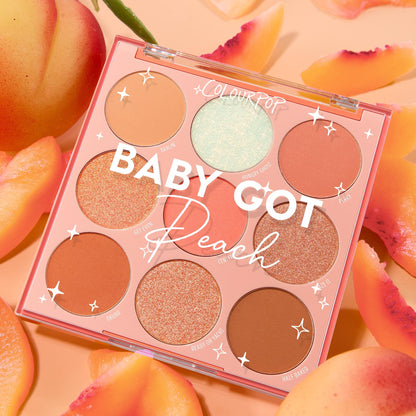Baby Got Peach ColourPop Shadow Palette showcases nine peachy mattes and shimmers under a clear lid, the 9-pan arranged top-down and surrounded by ripe peach slices on a soft apricot backdrop.