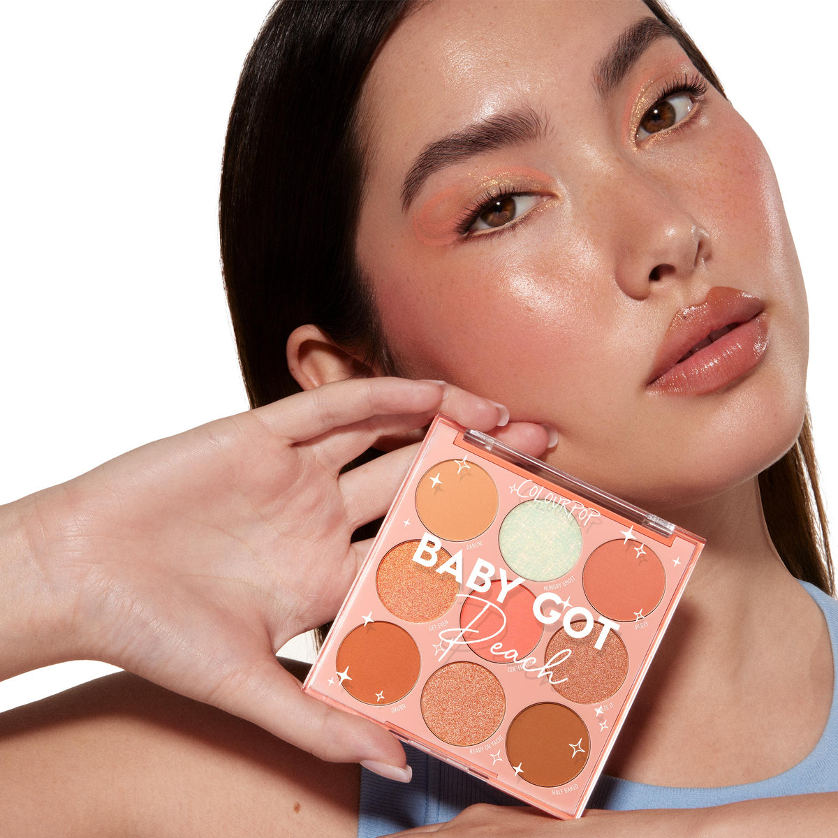 Model holds Colourpop Baby Got Blush shadow palette set close to her face, wearing soft peachy monochromatic palettes eye and cheek makeup that matches the warm matte and shimmer peach shades in the compact.