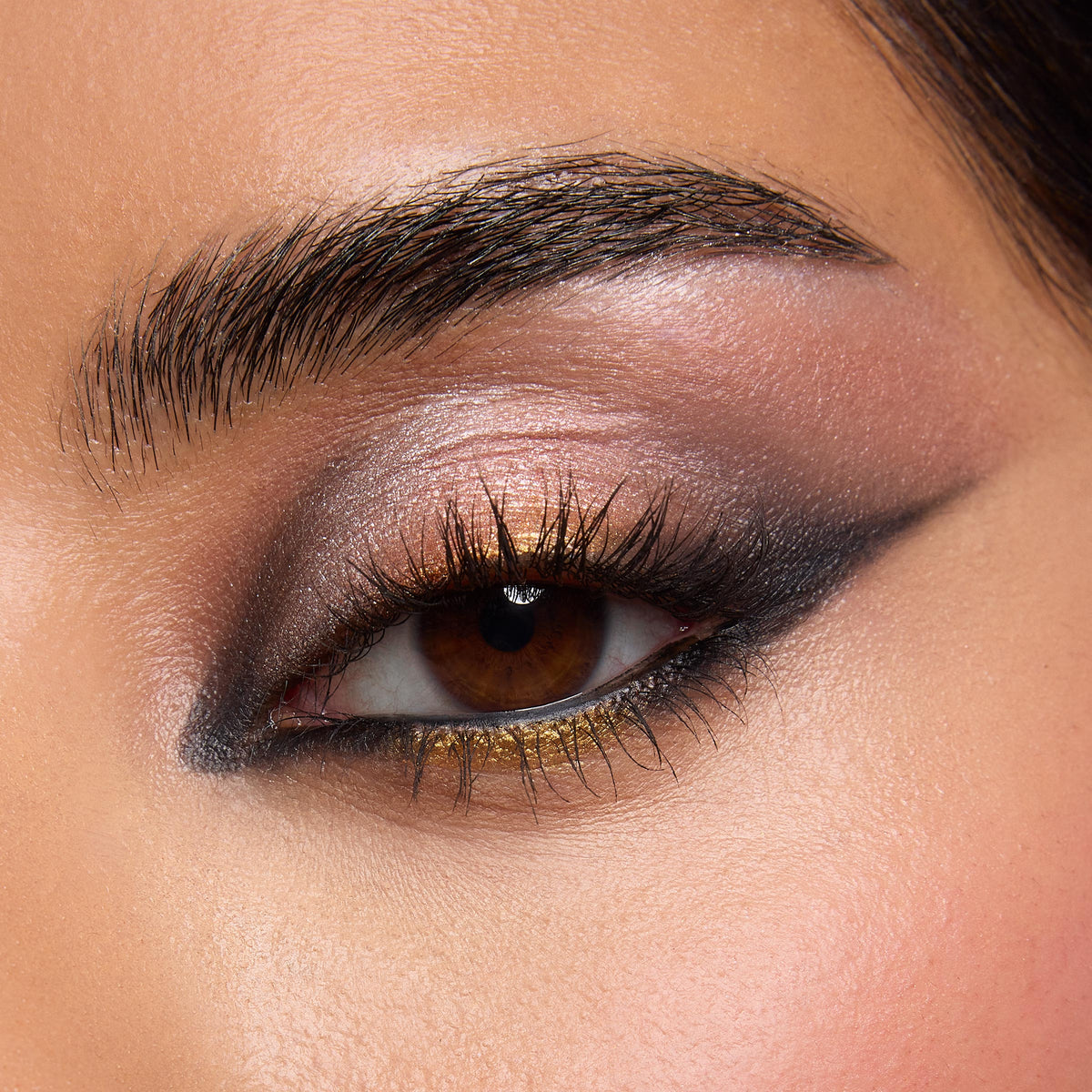 Brown eye showcasing shimmering bronze, taupe, and charcoal shades from the Precious Metals ColourPop Shadow Palette, blended into a smoky wing with metallic gold along the lower lash line, close-up highlighting rich pigment and smooth blendability.