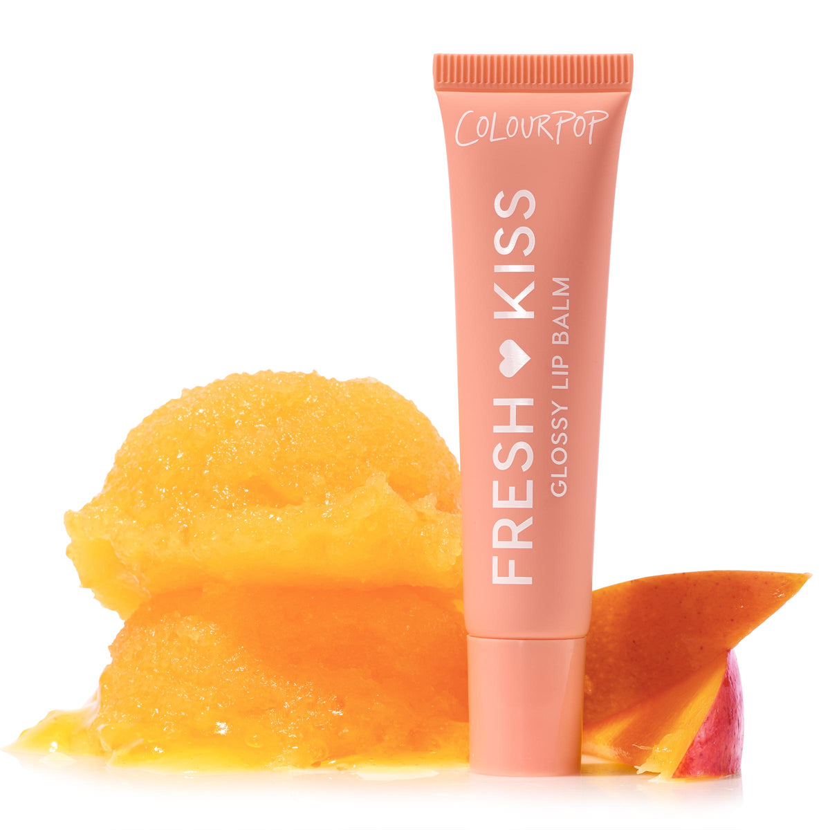 ColourPop Fresh Kiss Glossy Balm in Mango Sorbet stands upright in a coral squeeze tube labeled “Fresh Kiss,” beside two melting scoops of mango sorbet and a mango slice on a clean white background.