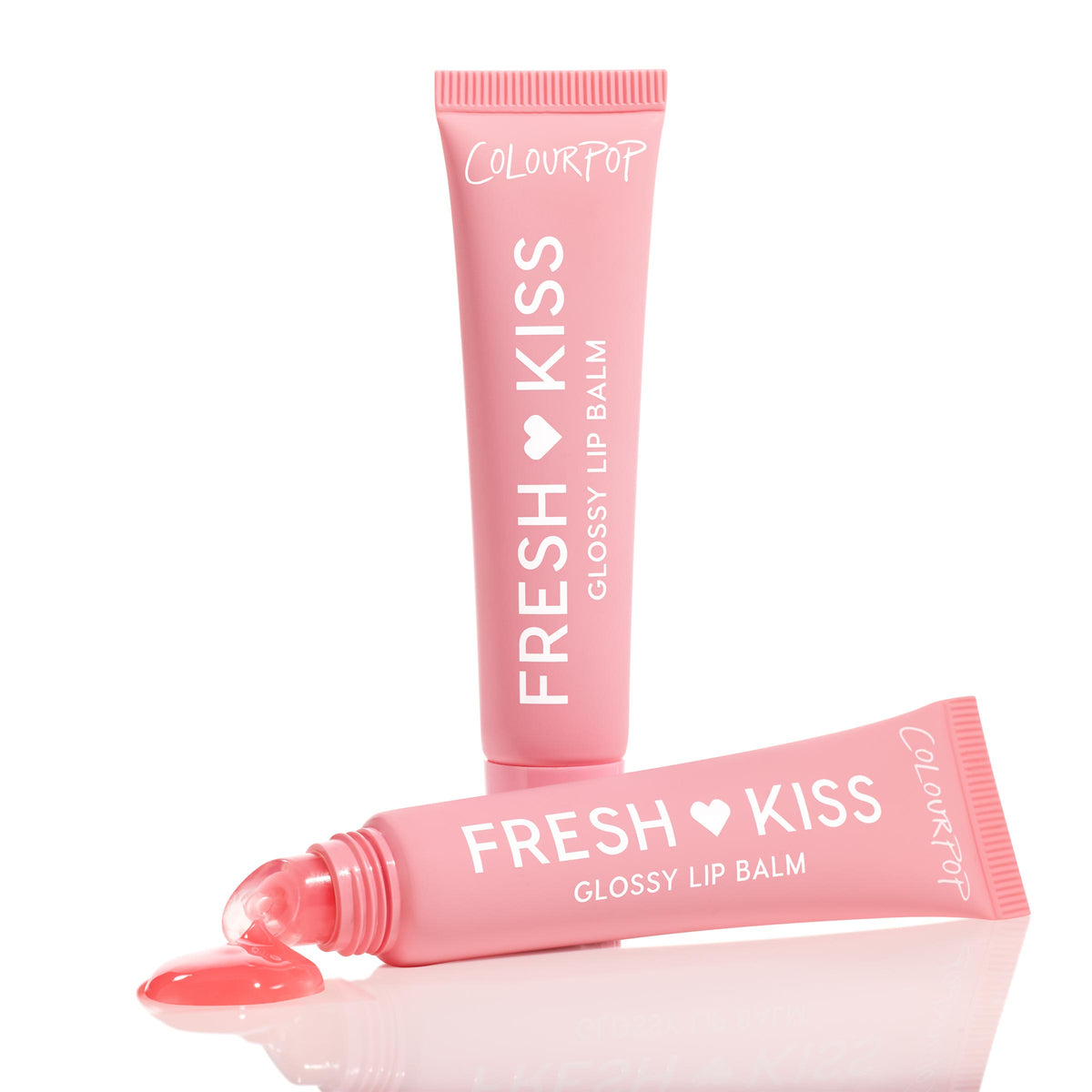 ColourPop Fresh Kiss Glossy Balm, Strawberry Milk shade - one pink tube upright and another squeezed with a rosy gloss bead at the slanted tip, shown on a reflective white surface in a clean studio close-up.
