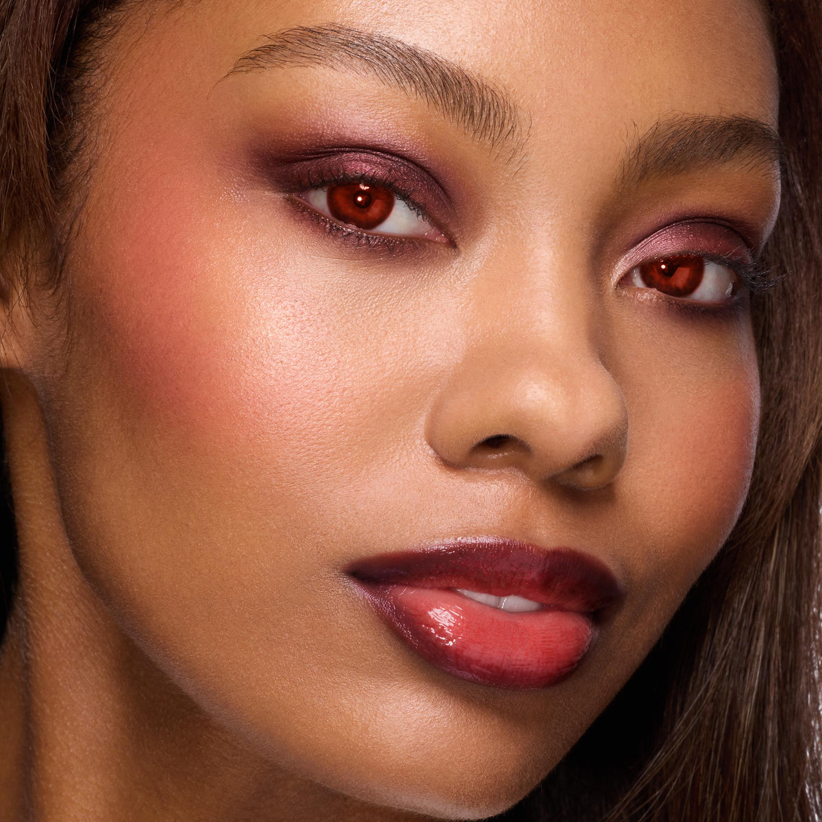 Close-up model showcases burgundy smokey eyes, warm blush, and glossy deep red lips from the Twilight New Moon x ColourPop Full Collection Set by ColourPop, highlighting bold red irises and vampire-inspired glam in a studio beauty shot.