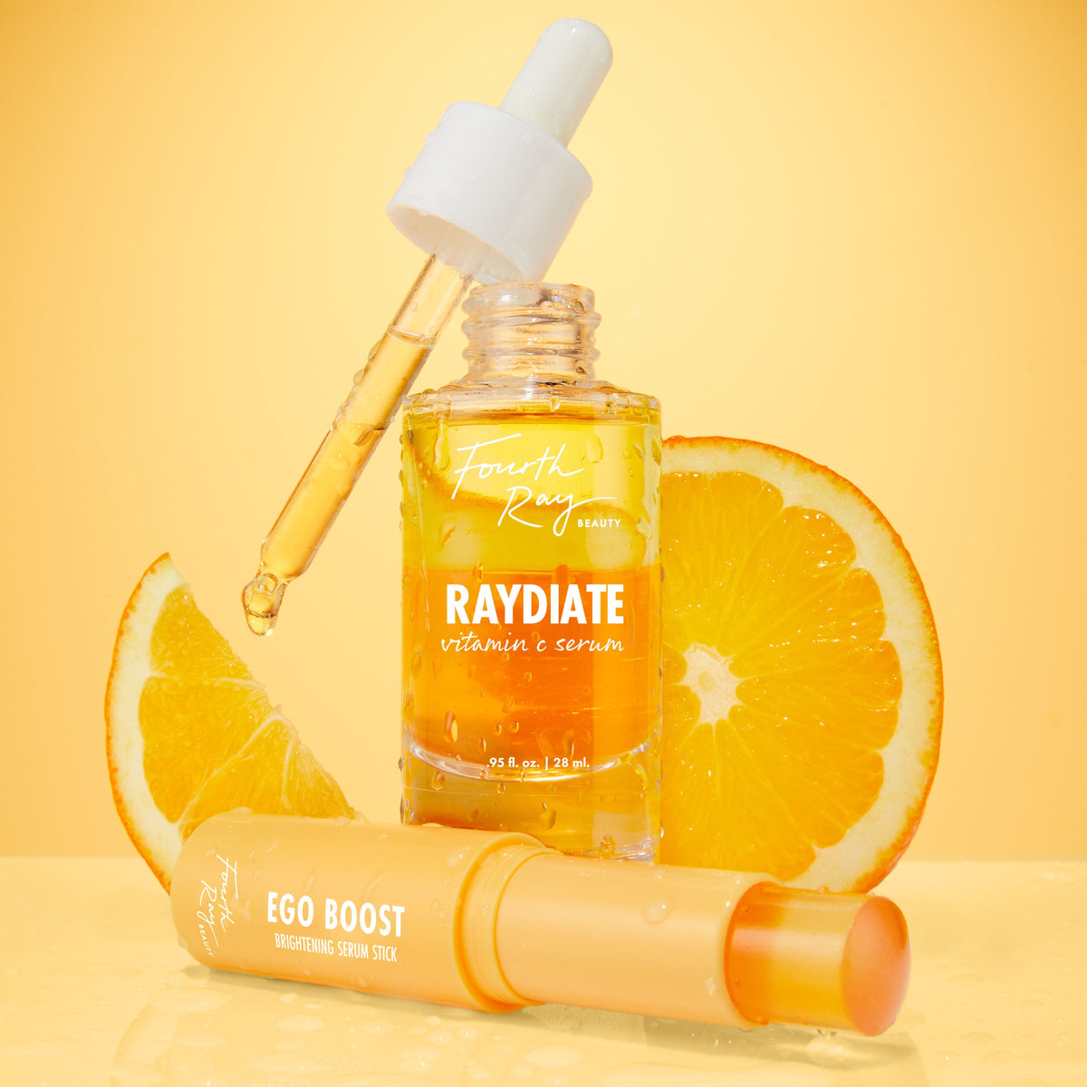 Get That Glow ColourPop Face Set with Fourth Ray Beauty Raydiate Vitamin C Serum and a dripping dropper beside Ego Boost Brightening Serum Stick, styled on a wet glossy surface with fresh orange slices and a warm golden backdrop.
