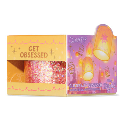 ColourPop Glitter Gel Floating Lights (Glitterally Obsessed) shown in a yellow windowed box with purple Tangled lantern artwork and ‘Get Obsessed’ text; iridescent pink-gold chunky glitter; 0.6 oz body glitter, Disney collaboration.