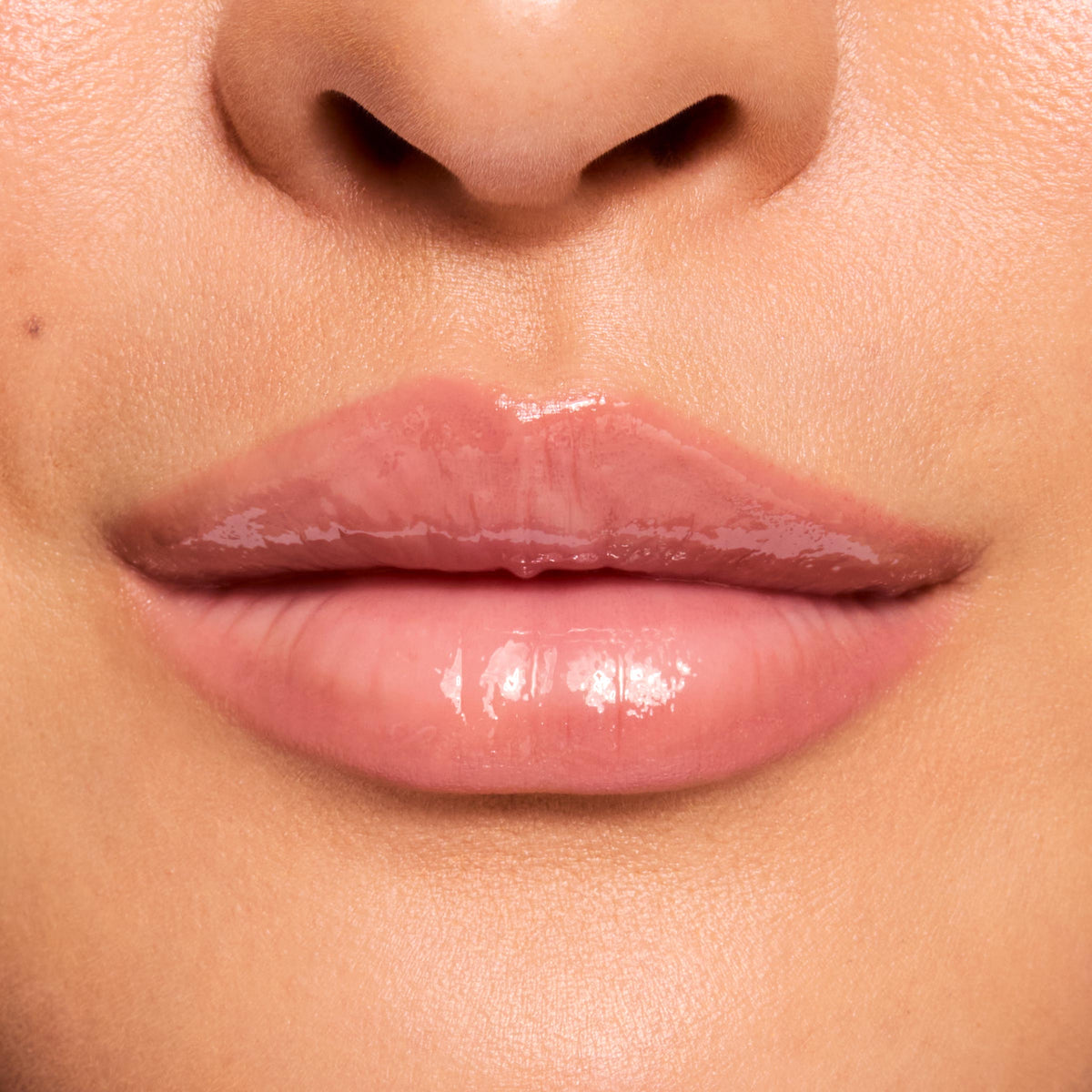 Glossy lips wearing ColourPop Fresh Kiss Glossy Balm in Strawberry Milk, reflecting a high-shine, sheer milky pink finish in a close-up swatch for a smooth, hydrated look.