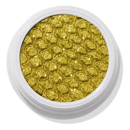ColourPop Super Shock Shadow Green Juice shimmering in a close-up, the metallic chartreuse green-gold shade sparkles across a dimpled honeycomb texture, housed in an open white round pot on a clean studio background.
