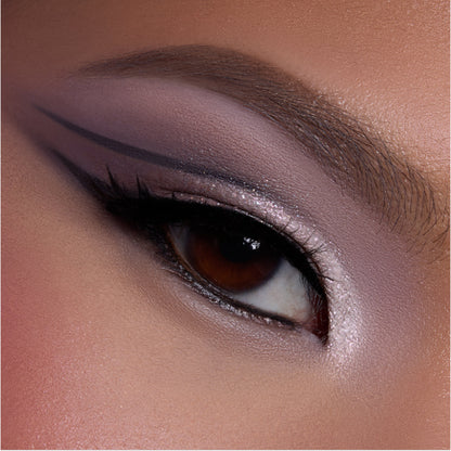 Close-up of a brown eye wearing shimmering mauve and pink shadow from the Heart to Get shadow palette, with sharp graphic black liner and highlighted inner corner, showcasing bold glam eye makeup detail.