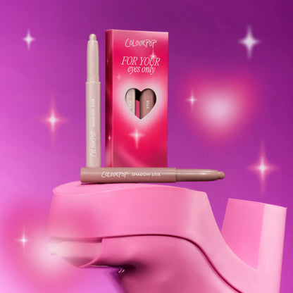 ColourPop For Your Eyes Only Shadow Stix from the Heart to Get collection standing beside its pink gradient box with heart-shaped cutout, styled on glossy pink heels against a sparkling magenta background.