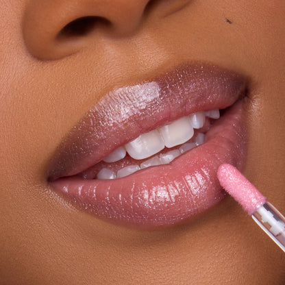 Close-up of a model applying Heart to Get 2 Die 4 Ultra Glossy Lip, showing shimmering pink gloss on smooth, full lips with a doe-foot applicator for a high-shine, hydrated finish.