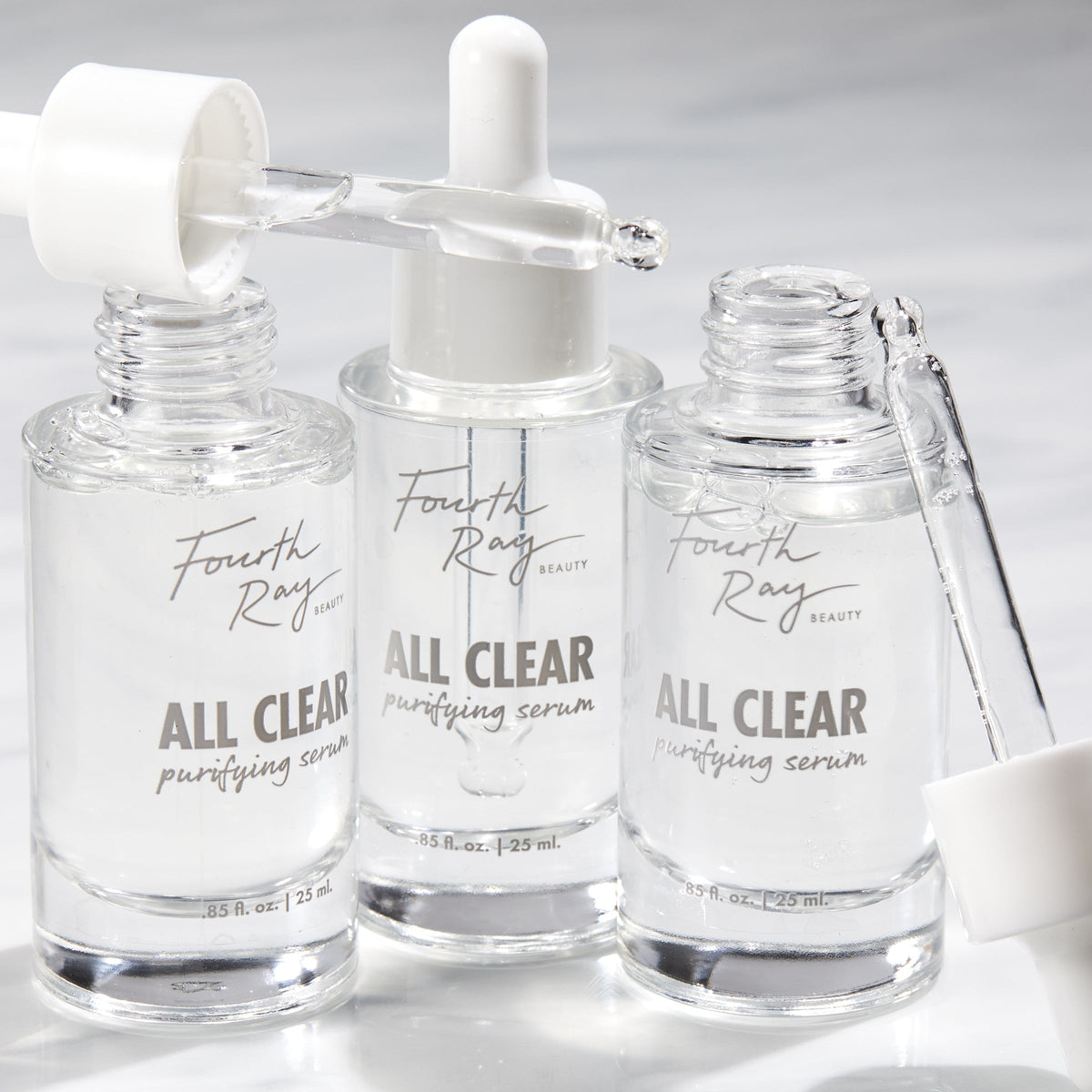 Fourth Ray Beauty All Clear Purifying Serum, a ColourPop Face Serum, three clear 0.85 fl oz (25 mL) glass dropper bottles with pipettes releasing transparent drops on a bright white surface.