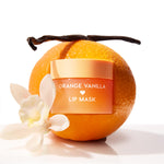 Orange Vanilla ColourPop Lip Mask jar gleaming with a peach-gold lid, sitting against a fresh orange as a vanilla bean and white blossom frame it, styled on a bright white background to highlight the citrus-vanilla scent and hydrating treatment.