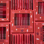 ColourPop Bring The Heat Lippie Pencil set arranged in a flat lay, showcasing creamy lip liners in reds, pinks, and berry tones; boxed and loose pencils surround the main kit on a red background with lips, stars, and lightning graphics.