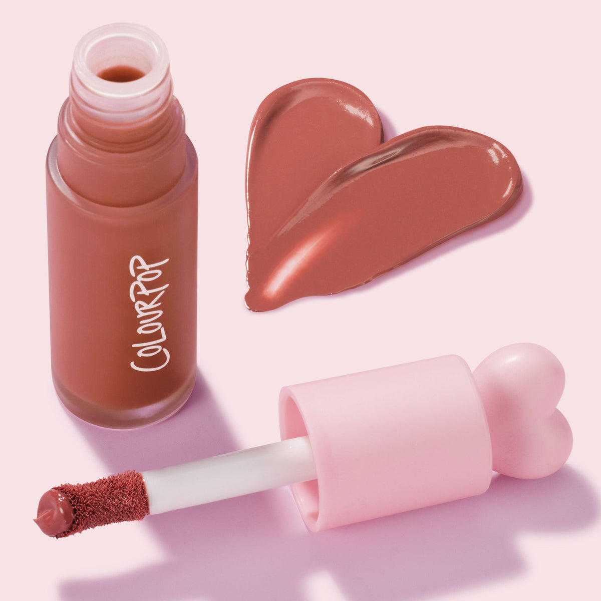Culver City ColourPop Liquid Blush swatched in a warm terracotta rose, with a doe-foot applicator and pink heart-shaped cap beside a frosted bottle, glossy pigment forming a heart on a pastel pink background.