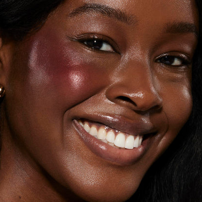 Wine n' Dine ColourPop Liquid Blush creating a dewy berry glow on a smiling model’s cheeks in a close-up, highlighting glossy skin and a radiant sheen for everyday glam.