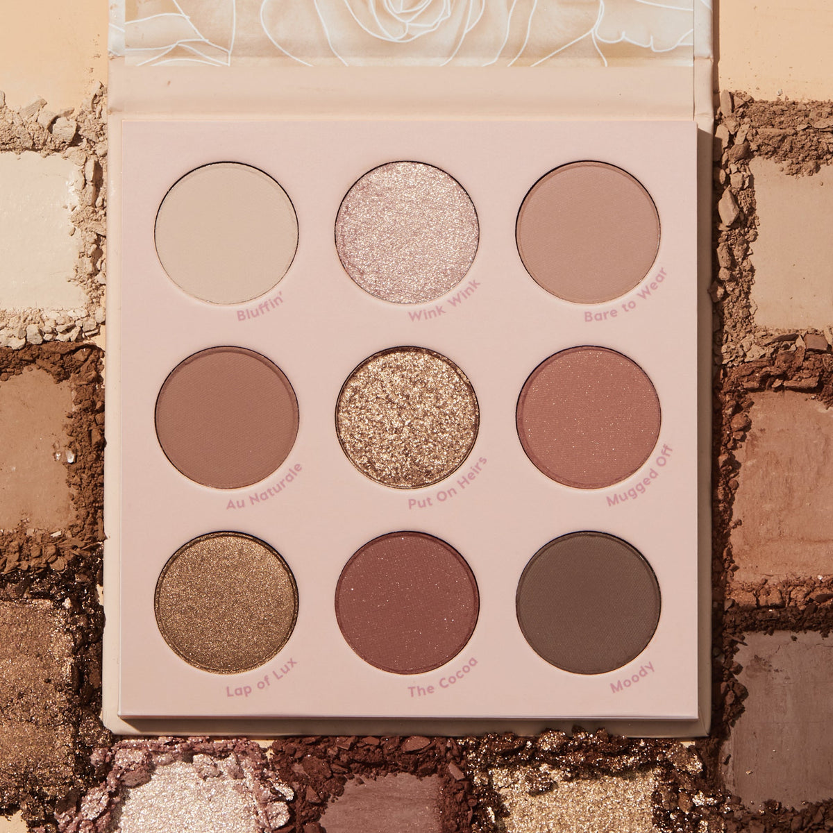 Nude Mood ColourPop Shadow Palette displaying nine neutral eyeshadows - matte and shimmer - labeled Bluffin', Wink Wink, Bare to Wear, Au Naturale, Put On Heirs, Mugged Off, Lap of Lux, The Cocoa, and Moody, set on crushed nude swatches.