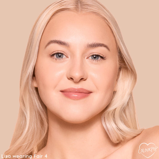 Model's face wearing ColourPop Pretty Fresh Tinted Foundation Balm in Fair 4, showcasing a dewy, natural finish and even skin tone with soft glossed lips, against a warm beige studio background to highlight the fair shade match.