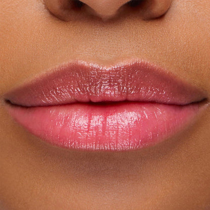 Glossy lips wearing Sing, a ColourPop pH Lip Balm, reveal a soft rosy pink tint that adapts to skin pH, with smooth, hydrated shine in a close-up lip swatch.