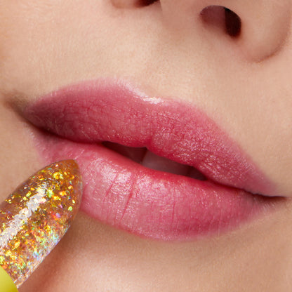 Thunderbolt ColourPop pH Lip Balm slicking onto lips, a clear jelly stick with gold iridescent flakes that reacts to pH to leave a glossy pink tint; close-up beauty shot showing hydrated, shiny finish.