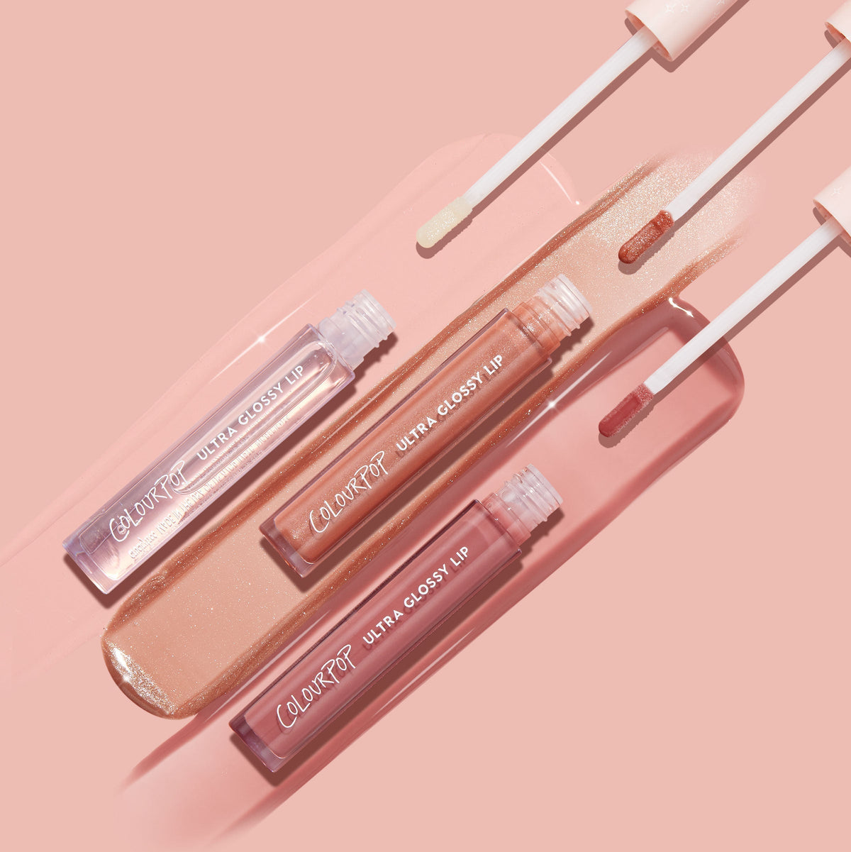 Perfect 4 U ColourPop Ultra Glossy Lip bundle shows three open tubes with doe-foot applicators swiping glossy nude, peach shimmer, and rosy pink swatches on a blush backdrop, showcasing a high-shine finish.