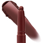 Plum Tart ColourPop Shadow Stix gliding a deep plum-brown eyeshadow swipe, the creamy retractable stick shown with a smooth smudged swatch on a white background to highlight rich color payoff.