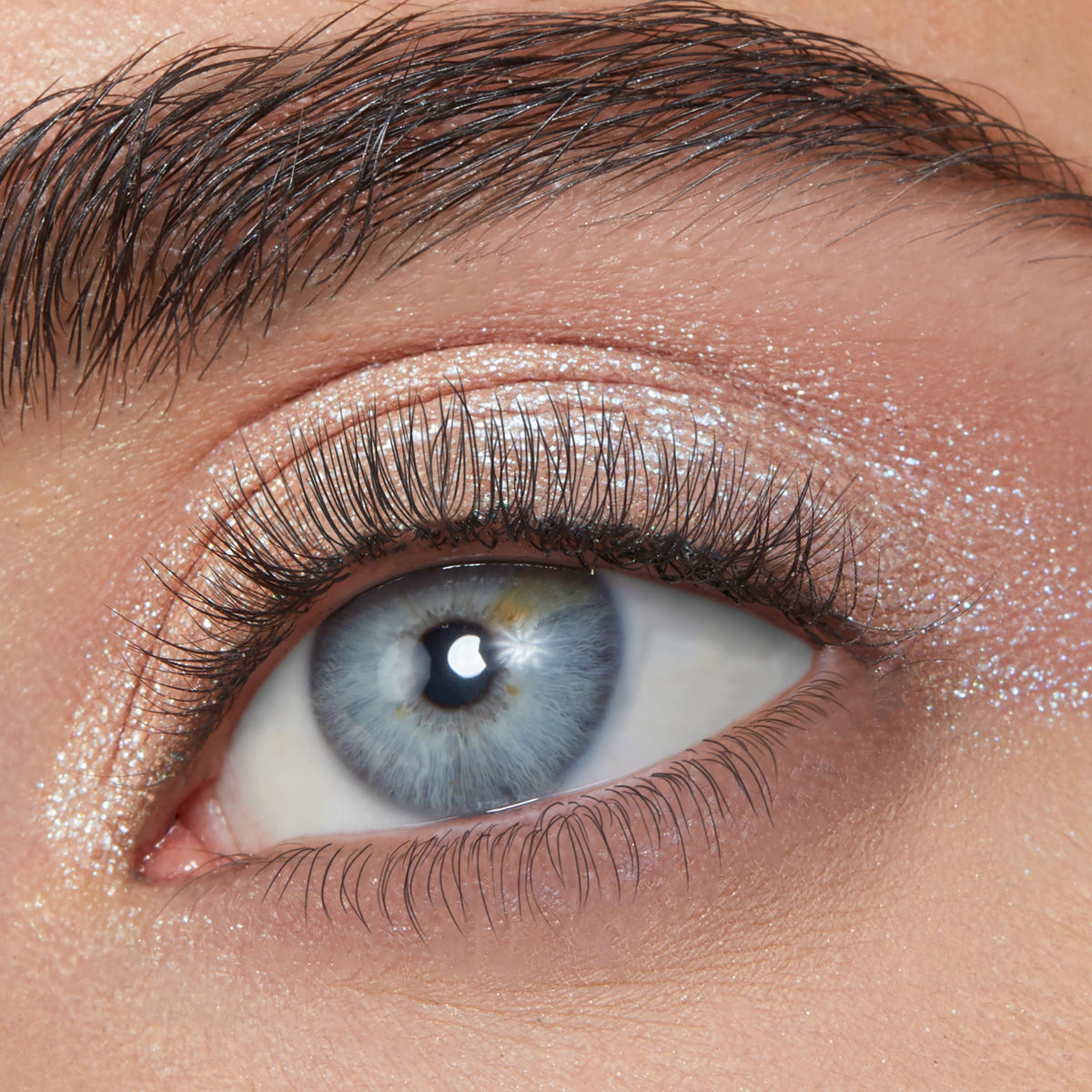ColourPop Sailor Super Shock Shadow, a shimmery icy silver with blue reflects, swept across the eyelid and inner corner, catching light; close-up of an eye with natural lashes highlights the high-shine, sparkly finish.