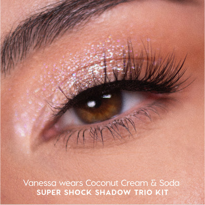 Close-up of a brown eye wearing Sweet Sips Super Shock Shadow in shimmering Coconut Cream & Soda, showing glittery champagne-pink lid color and long voluminous lashes, promoting the full collection set trio kit makeup look.
