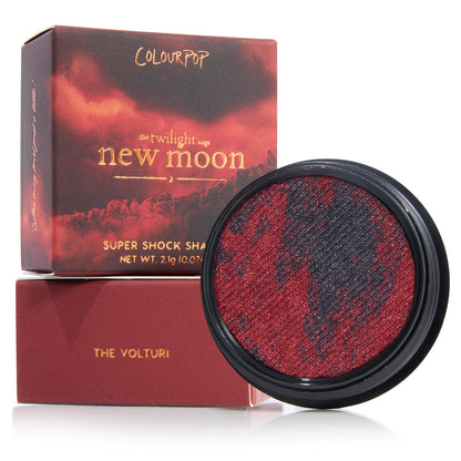 The Volturi eyeshadow single displays marbled crimson and charcoal shimmer in a round black pan, set beside Twilight Saga: New Moon box and matching sleeve, ColourPop Super Shock Shadow (2.1 g) on a white background.