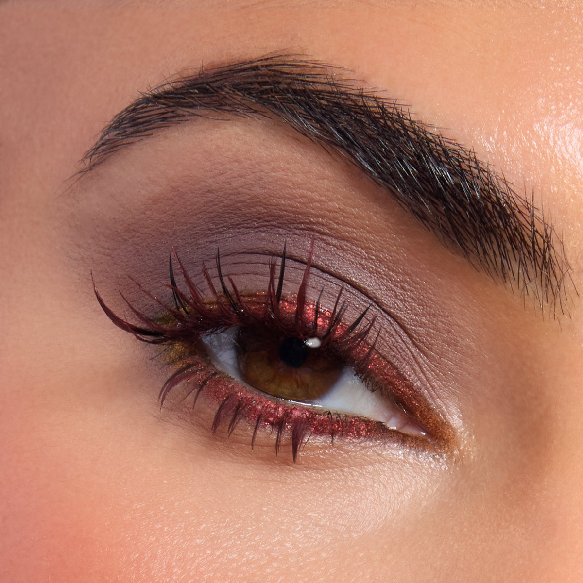 Shimmery red and olive eye look highlights a hazel eye, with metallic ruby liner and soft taupe crease from the Beware Ogre shadow palette, a ColourPop Shadow Palette, shown close-up to showcase sparkle detail and long lashes.