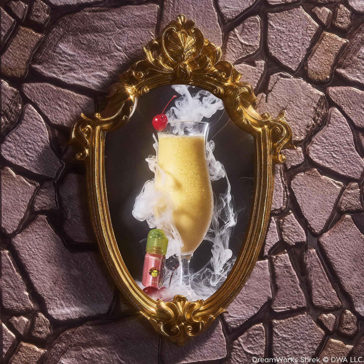 Ogress ColourPop Ultra Glossy Lip stands at the base of an ornate gold mirror, the pink lip gloss with green cap and ogre icon beside a smoky golden drink topped with a cherry, set against a medieval stone wall backdrop.