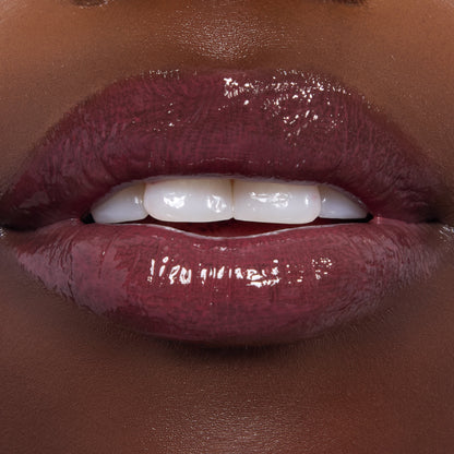 Glossed lips showcase ColourPop Ultra Glossy Lip in Short Lord, a deep berry‑plum shade with glassy, full‑coverage shine, applied evenly on smooth lips; tight macro shot highlighting the reflective finish for a product swatch.