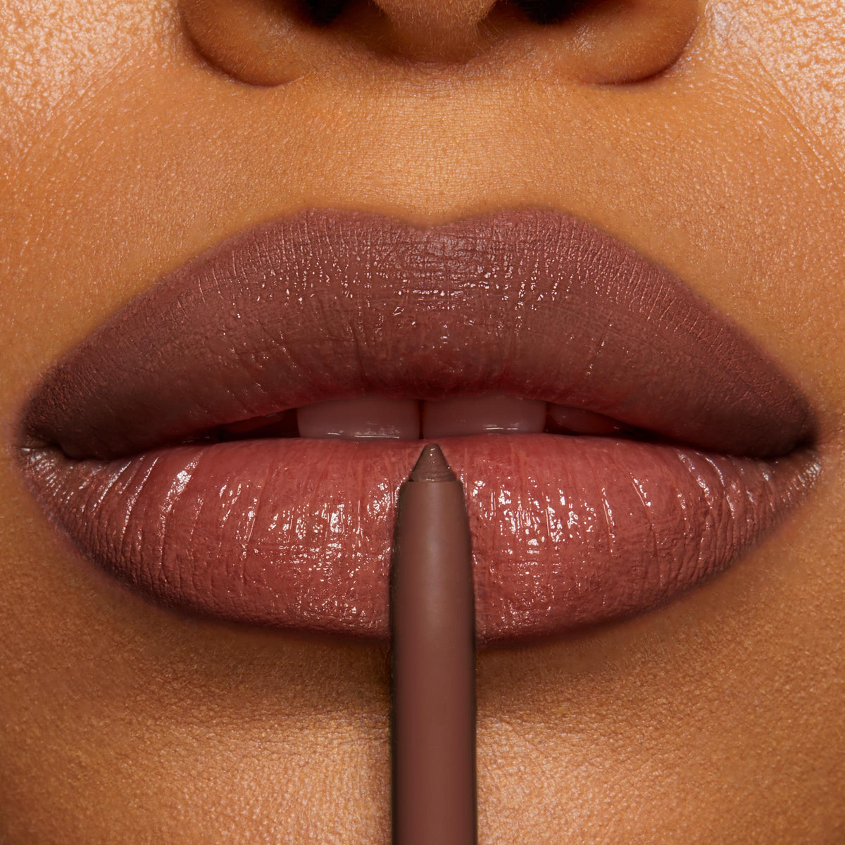 ColourPop So Juicy Plumping Lip Liner with Peptides in Slay outlines full lips in a rich brown‑nude; pencil tip centered at the cupid’s bow, creating crisp definition on glossy lips in a close-up studio shot.