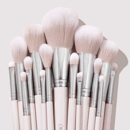 Soft pink makeup brushes with silver ferrules fan upright, showcasing powder, blush, and eyeshadow heads in a neat cluster on a neutral backdrop, part of The Ultimate Stunner ColourPop Shadow Palette & Brush Set for precise application.