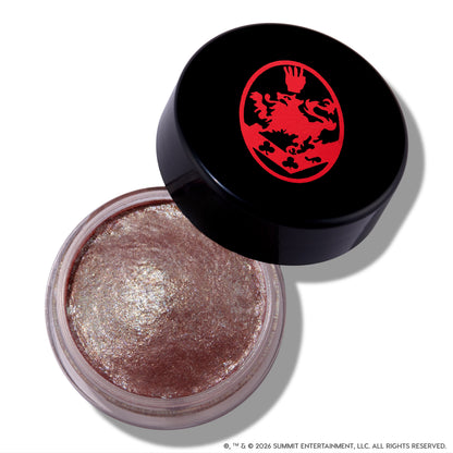 Open ColourPop Cullen Coven Jelly Much Shadow, a shimmery metallic taupe cream eyeshadow inspired by Twilight, sits in a clear round jar with a tilted black lid featuring a bold red crest logo on a white background.