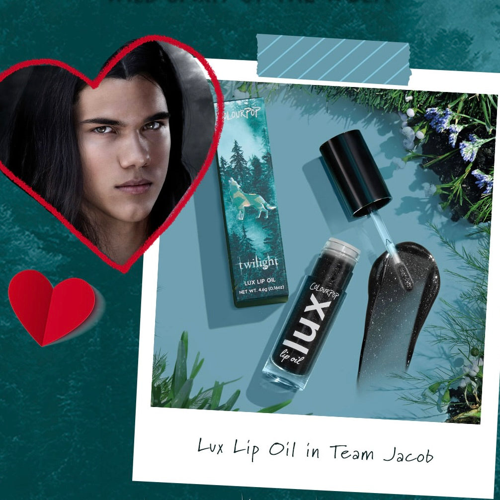 ColourPop Lux Lip Oil in Team Jacob, shown open with doe-foot applicator and a swatch of sheer black shimmer gloss; tube and Twilight forest box styled on a teal flat lay with foliage and a heart-framed portrait, from the Twilight collection.