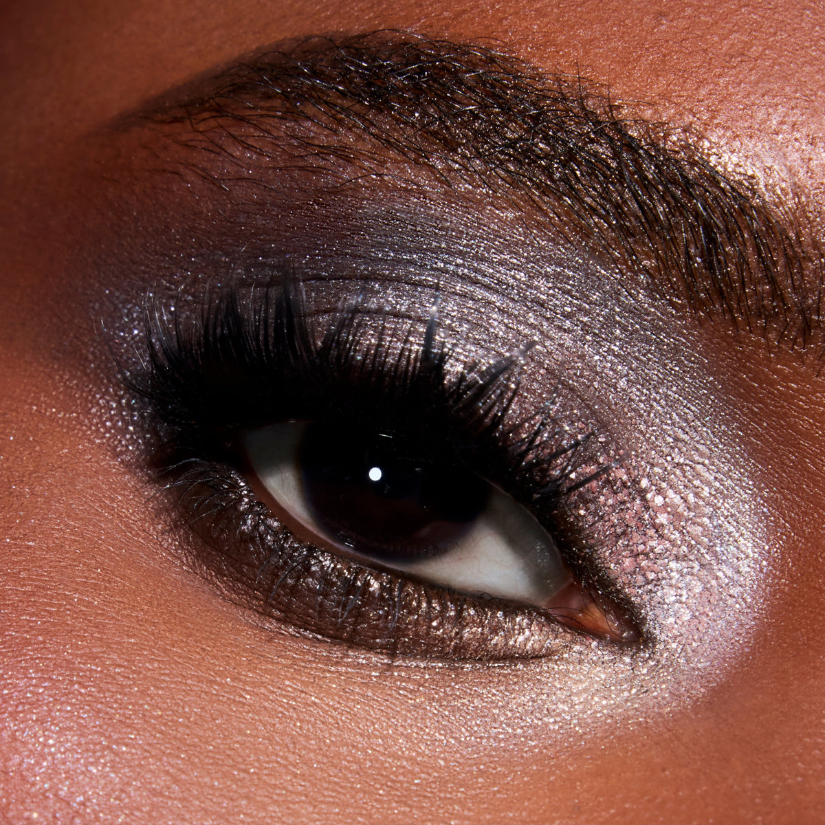 Close-up of a model’s eye wearing Twilight Coven Clash Jelly Much Duo, showing metallic smokey lavender and rose shimmer eyeshadow with dramatic black lashes for an intense, glossy evening eye look.